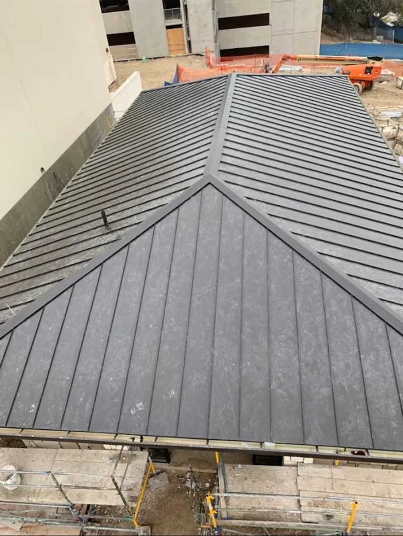 Commercial metal roof construction with crane equipment in Heath